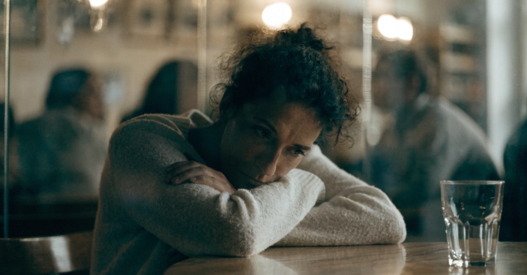 Woman sitting in a crowded meeting room looking introspective