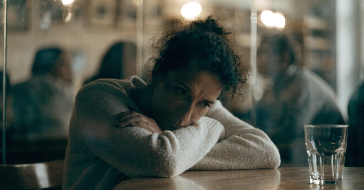 Woman sitting in a crowded meeting room looking introspective